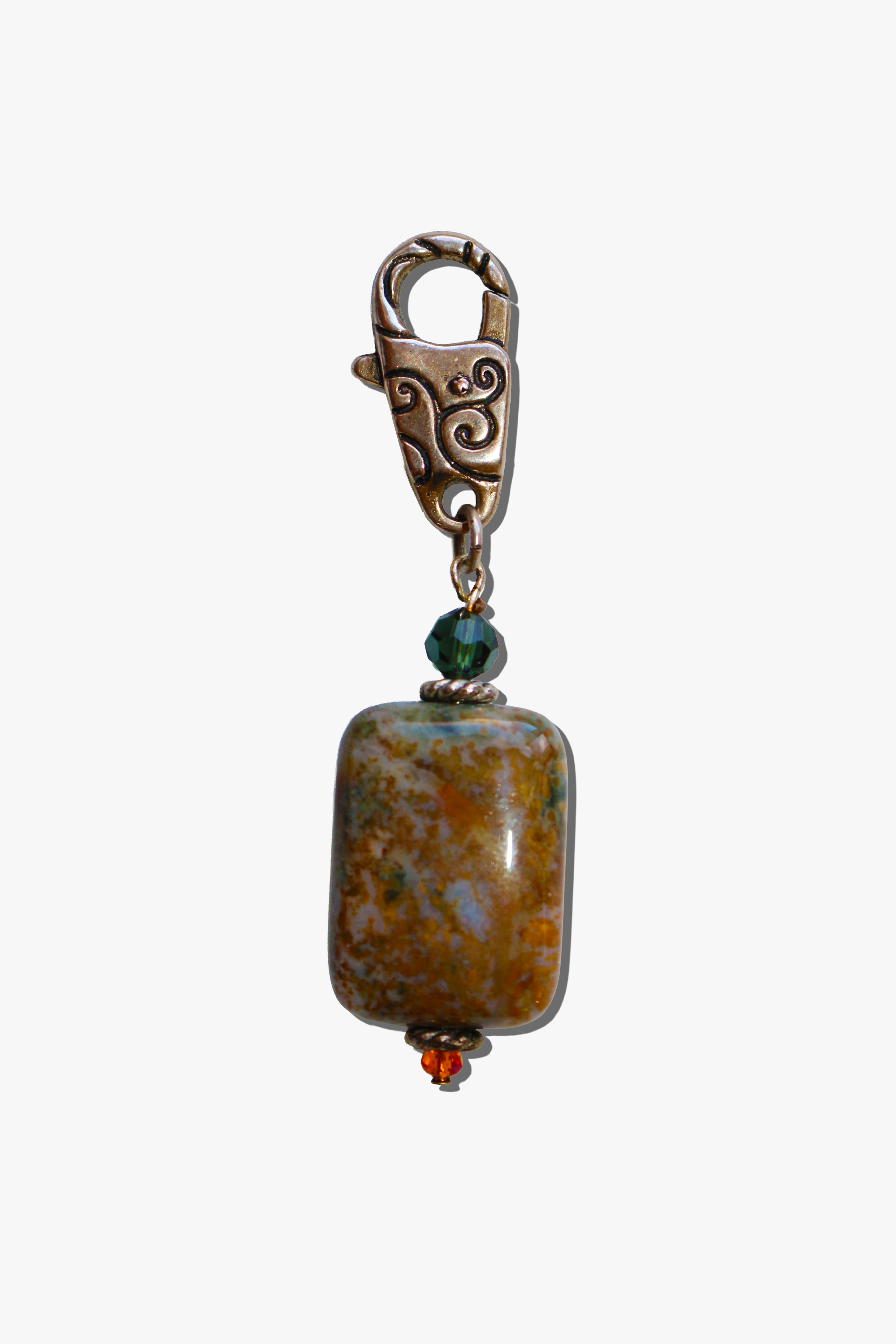 Jewelry charm with a large brown stone and green bead on a white background